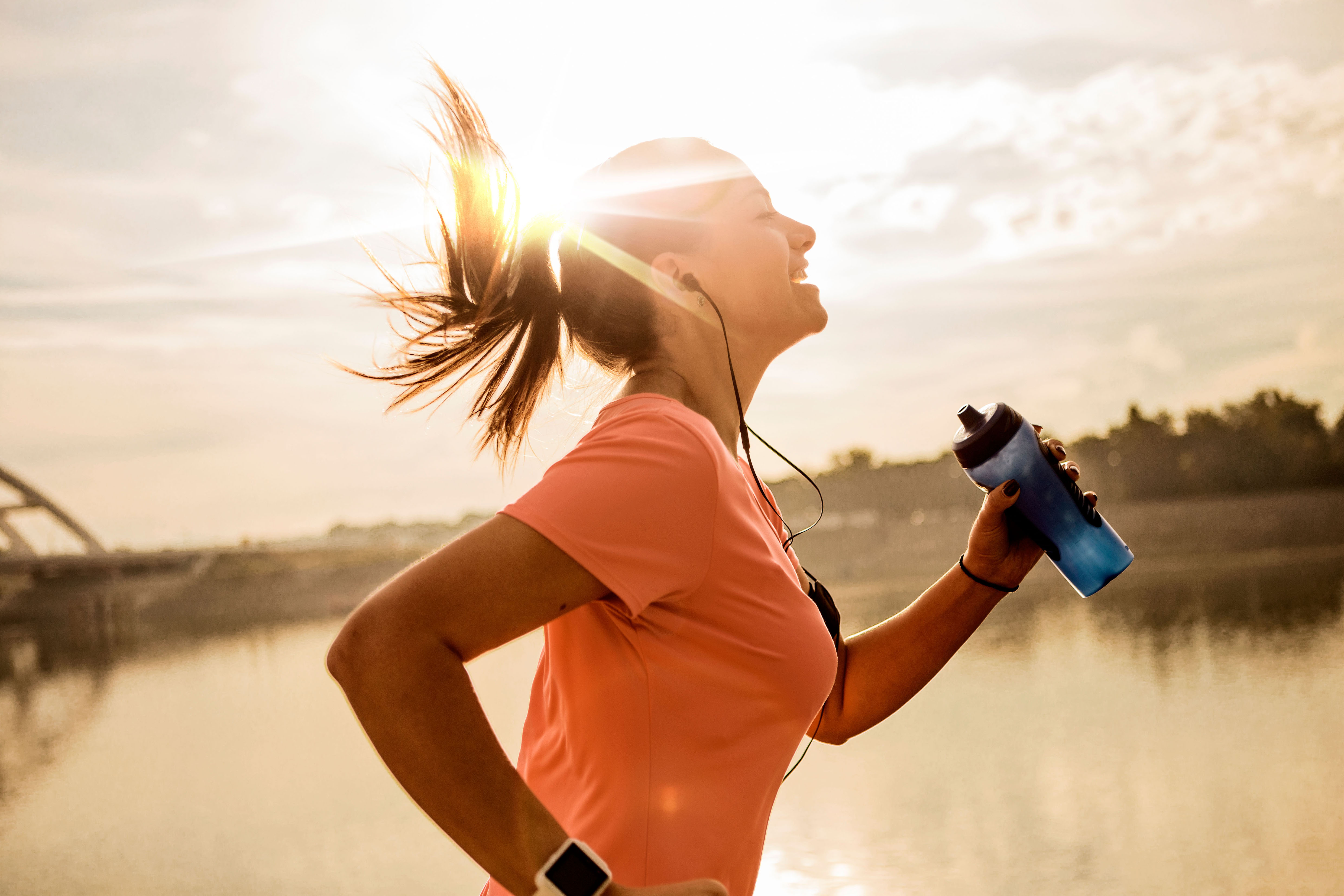 Junge Frau beim Joggen mit Wasserflasche in der Hand